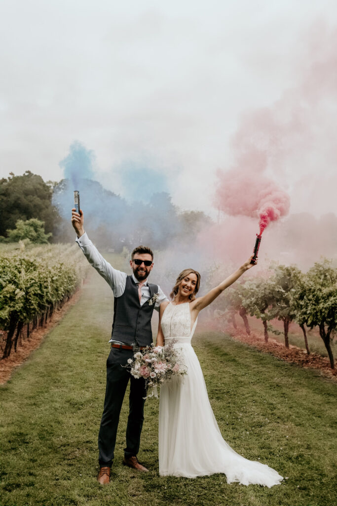 Bride and groom holding flares at vineyard wedding