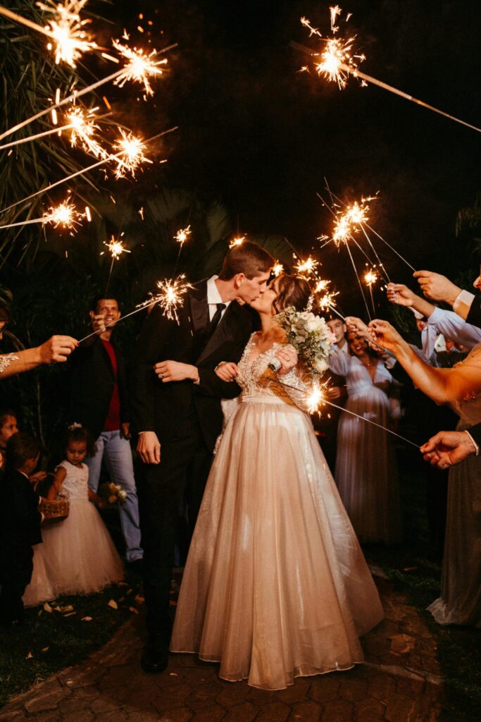 bride and groom kissing between guests raising sparklers